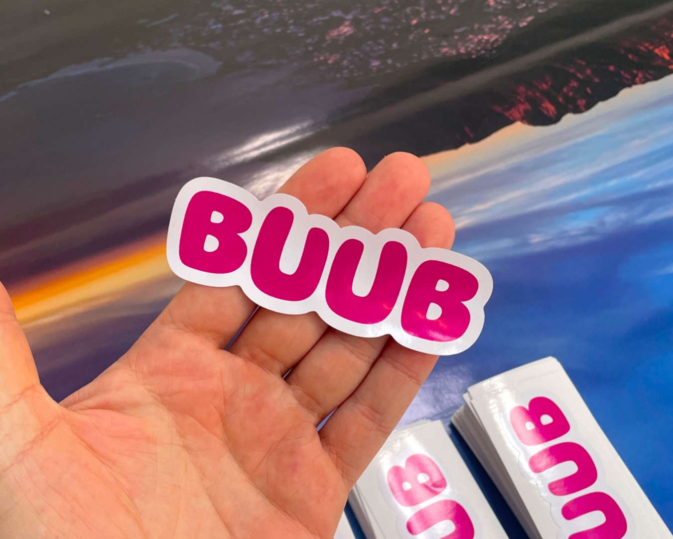 Pink bubble-letter BUUB die-cut sticker held in an open palm