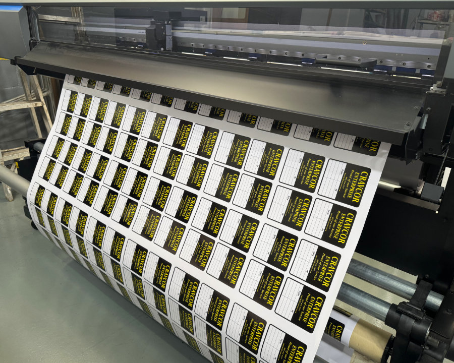 Roll of black and yellow Craycor Enterprise labels coming off the printer