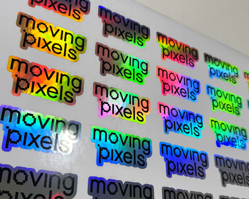 Rows of holographic Moving Pixels stickers catching rainbow light
