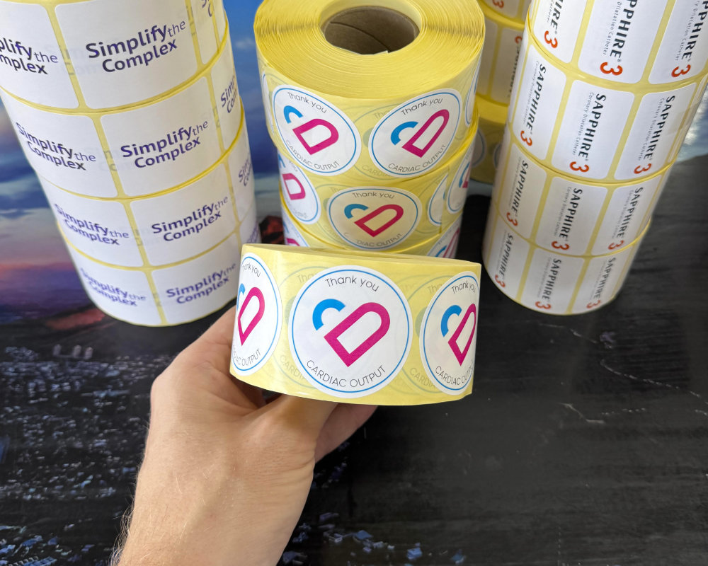 Rolls of white paper labels printed in three colours for pharmaceutical and medical device clients
