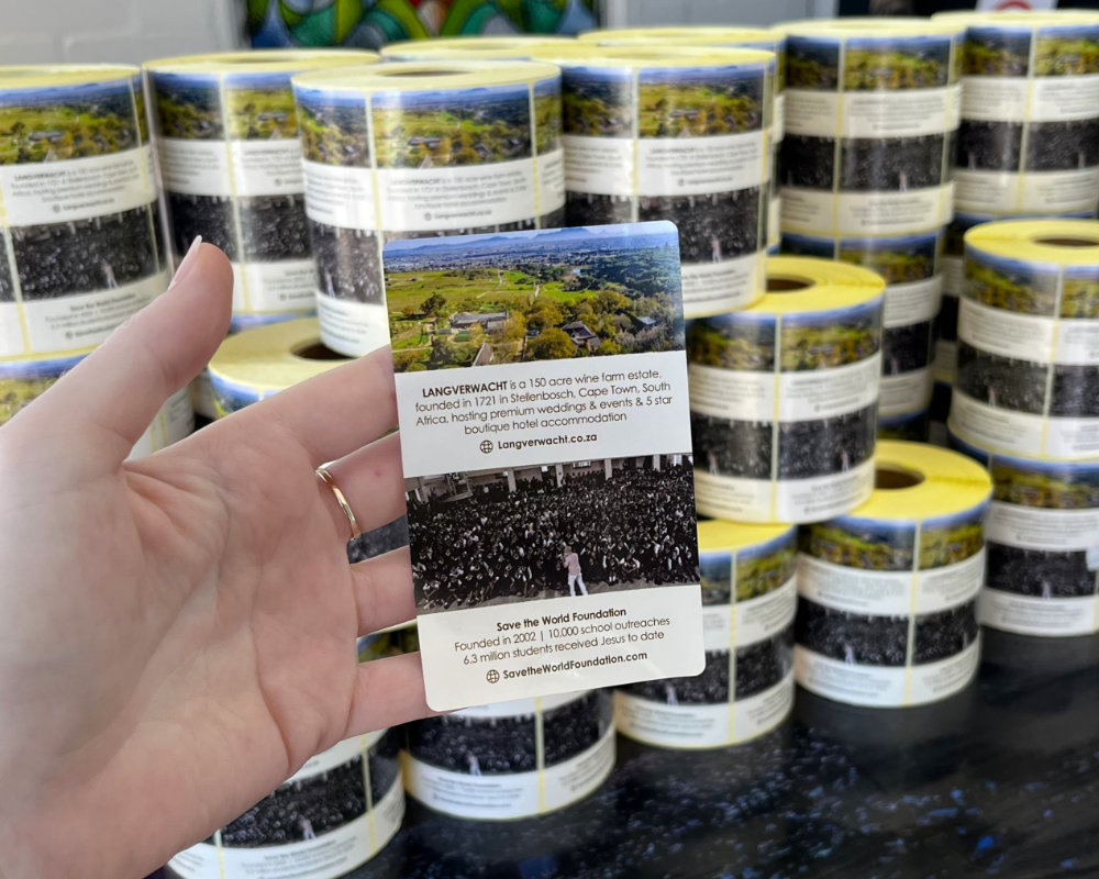 Poly-prop label for a wine estate held up in front of stacked rolls of labels