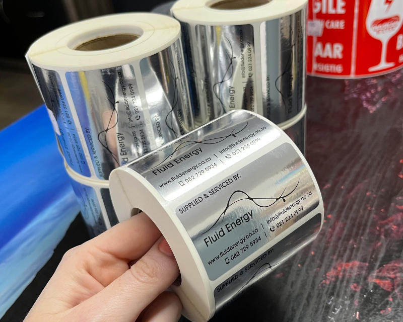 Rolls of silver foil labels printed with branding and contact details
